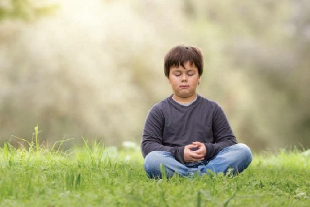 Young boy meditating in the park