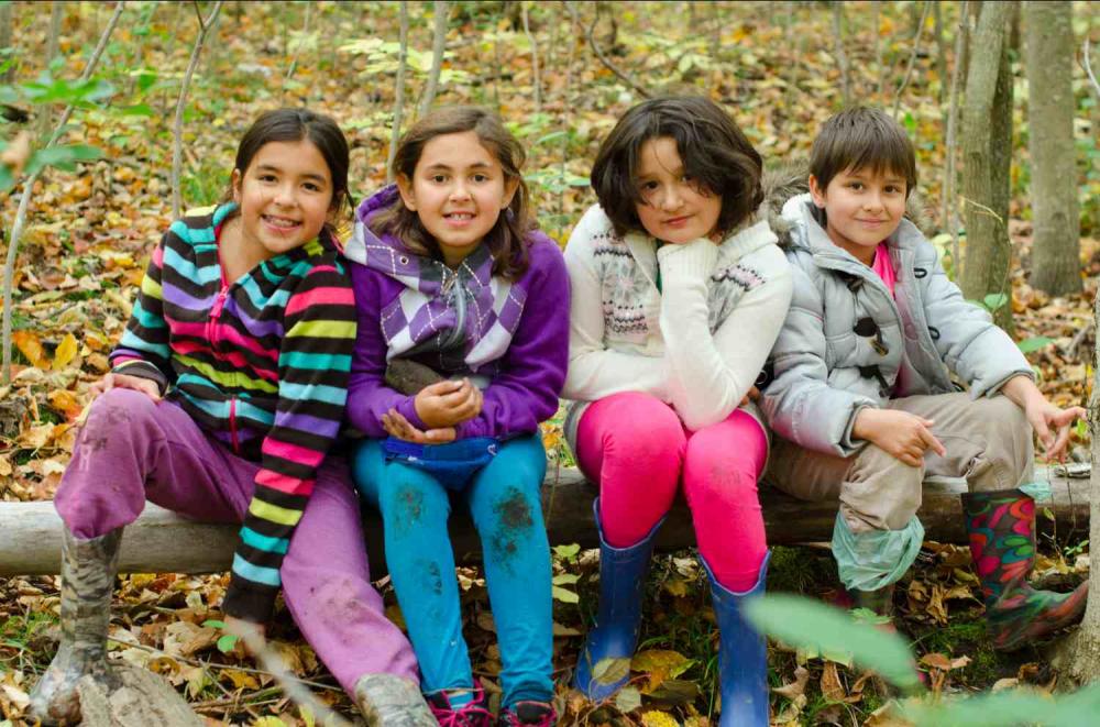 elementary students sitting on log in the woods