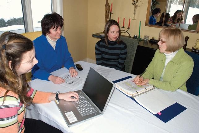 Female teachers sitting around table with open binders and a laptop