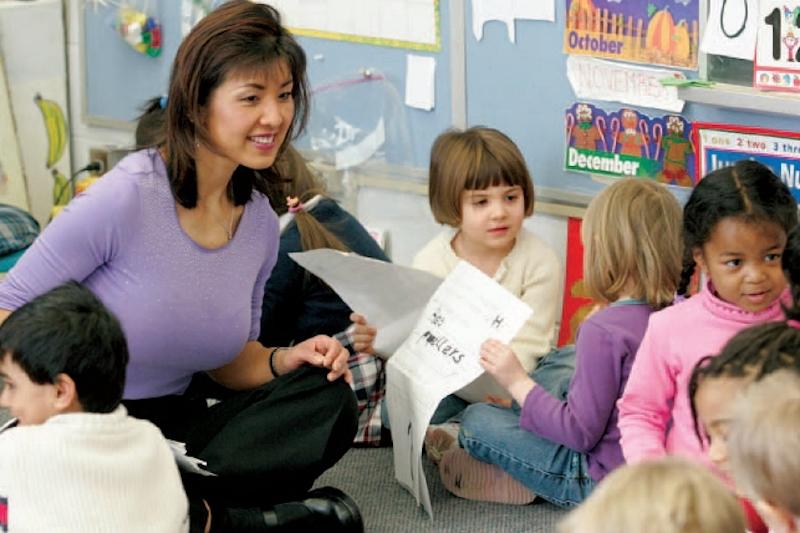 Teacher interacting with kindergarten students who have books