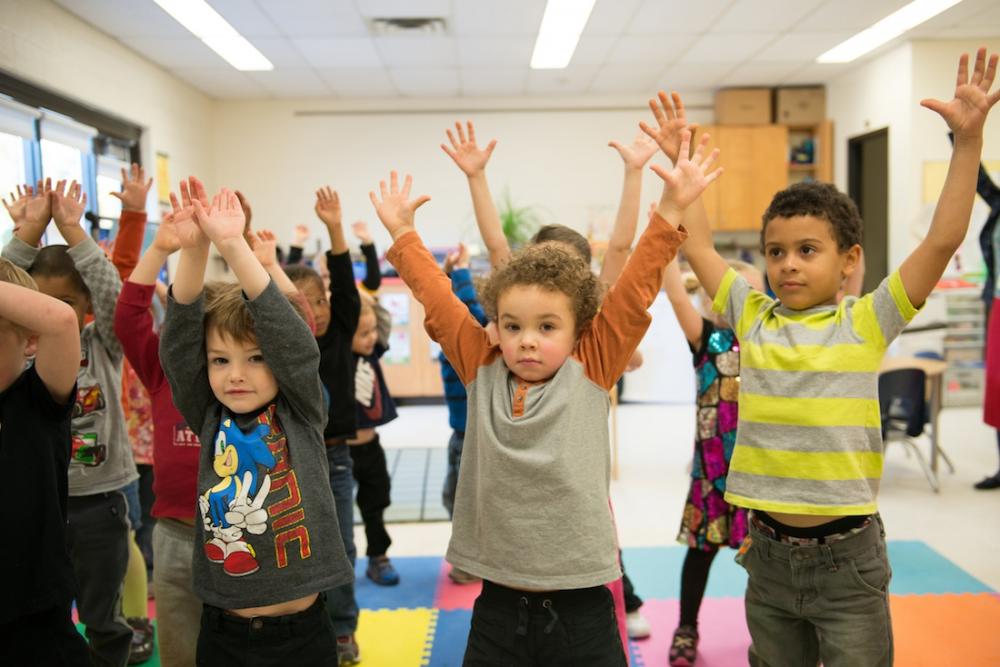 Young elementary students stretching in classroom