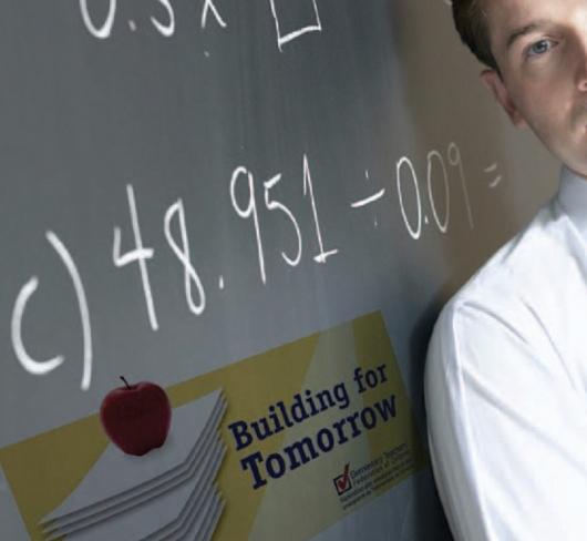 Teacher posing next to blackboard with mathematical equations written on it