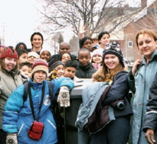 Teachers and students in winter clothing posing next to bus
