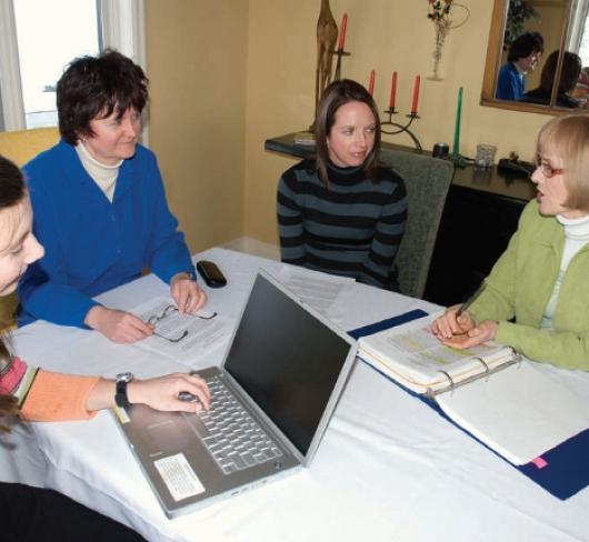 Female teachers sitting around table with open binders and a laptop