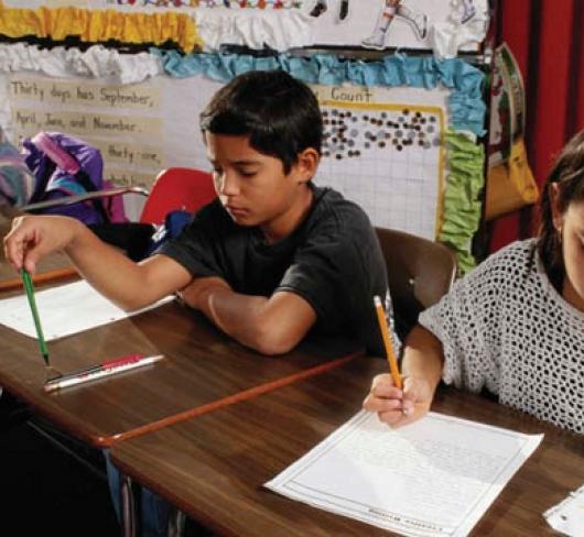 three students sitting at desks writing on paper