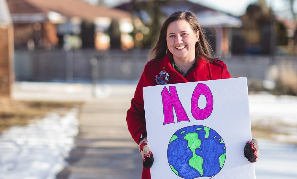 Woman standing outside holding sign