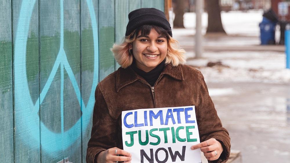 Savi Gellatly-Ladd holding "Climate Justice Now" sign