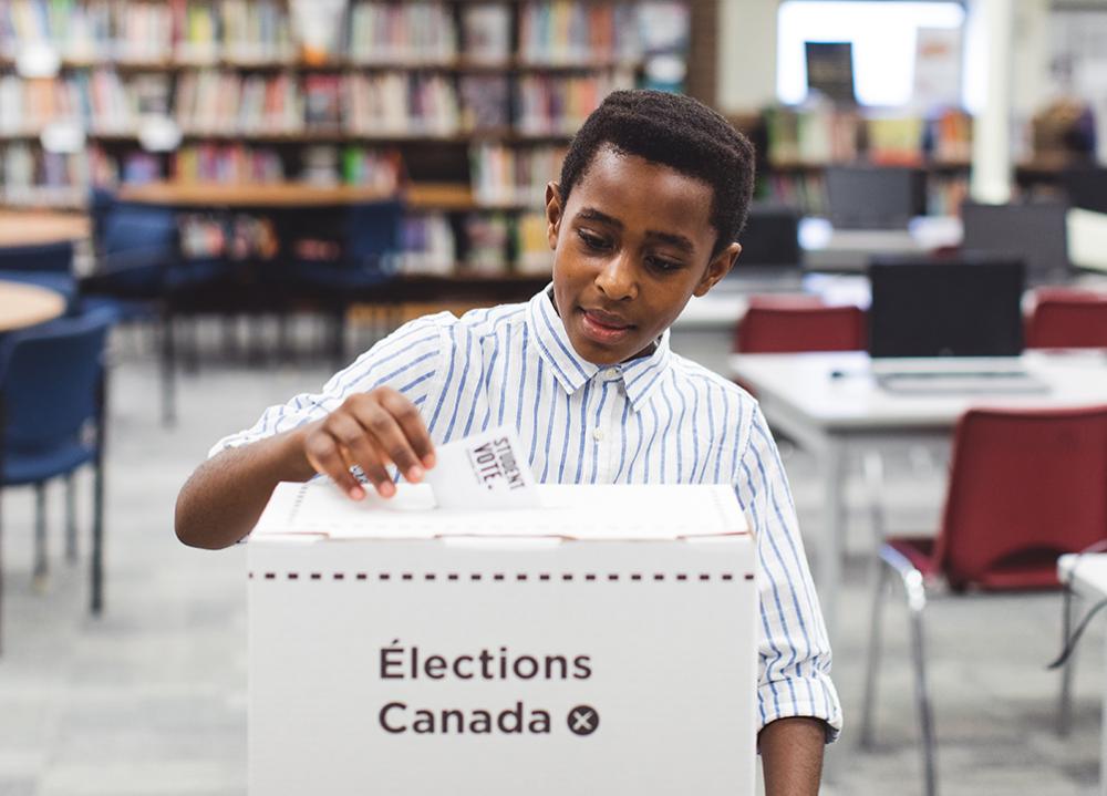 student placing voting card into elections box