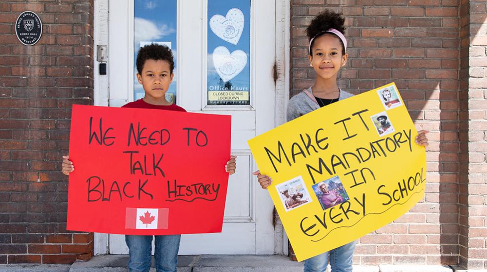 Children standing outside of school holding Black History posters they made