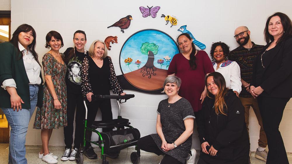 Staff posing in front of mural