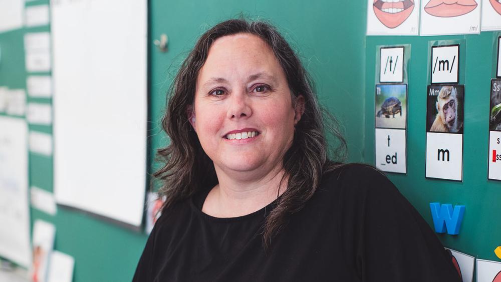 Kim Brown posing in front of classroom