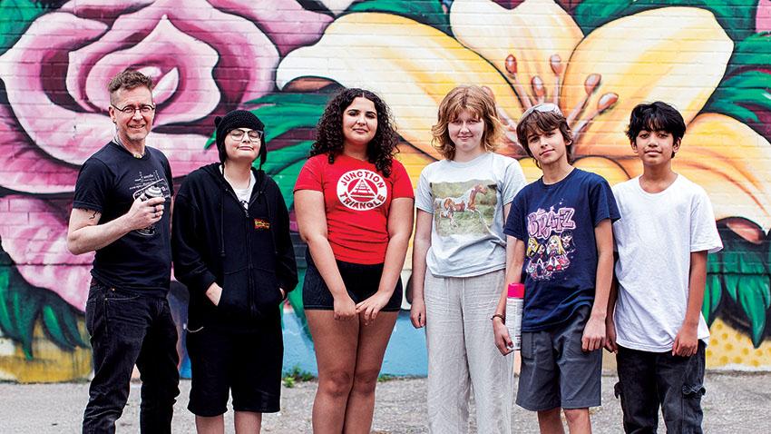 David Stocker and students posting in front of spray-painted mural