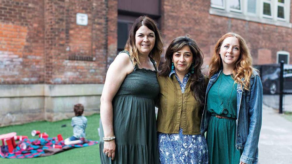 Three teachers posing outside of a school