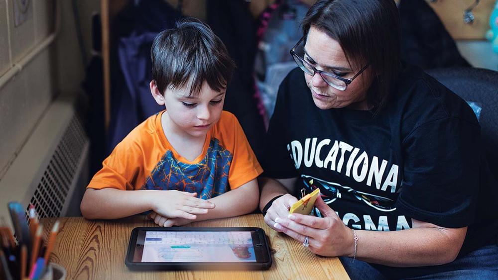 Nancy Campbell sitting with student looking at tablet