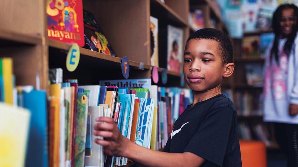 Black male student picking a book to read in the library