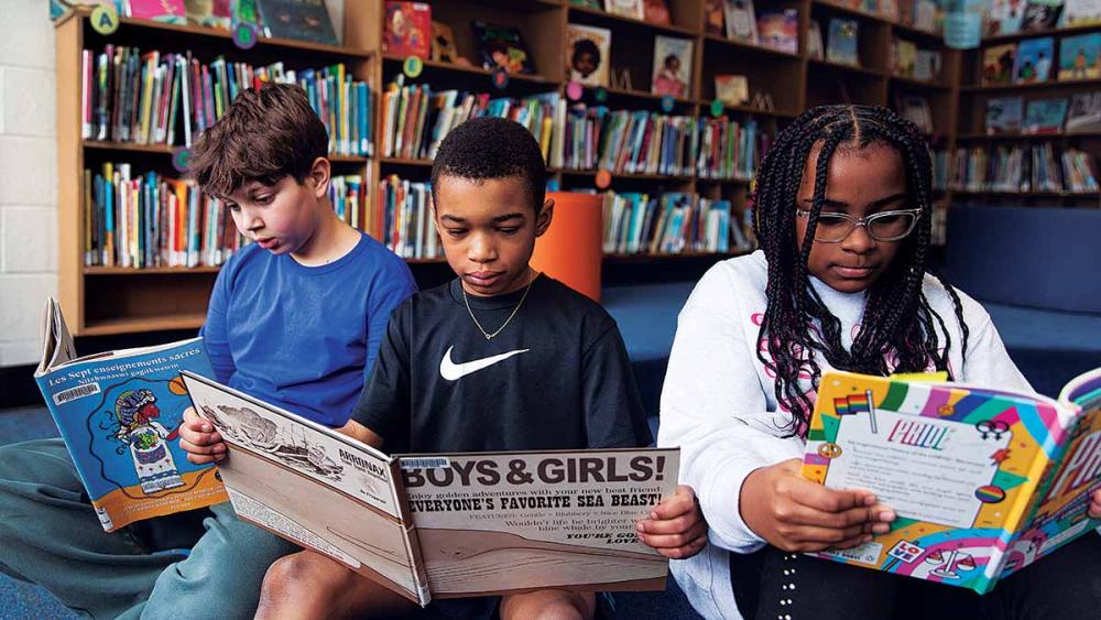 All three students reading together in the library