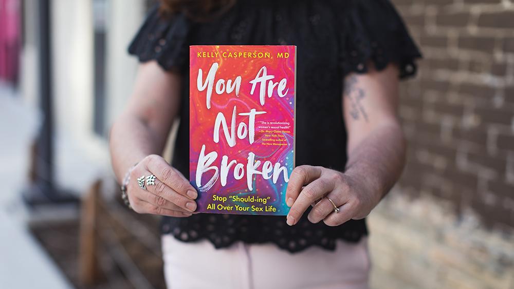 Lisa Boate holding up the book titled "Your Are Not Broken"