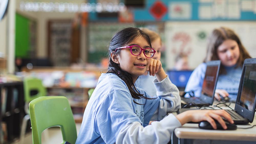 Young girl in classroom using a laptop