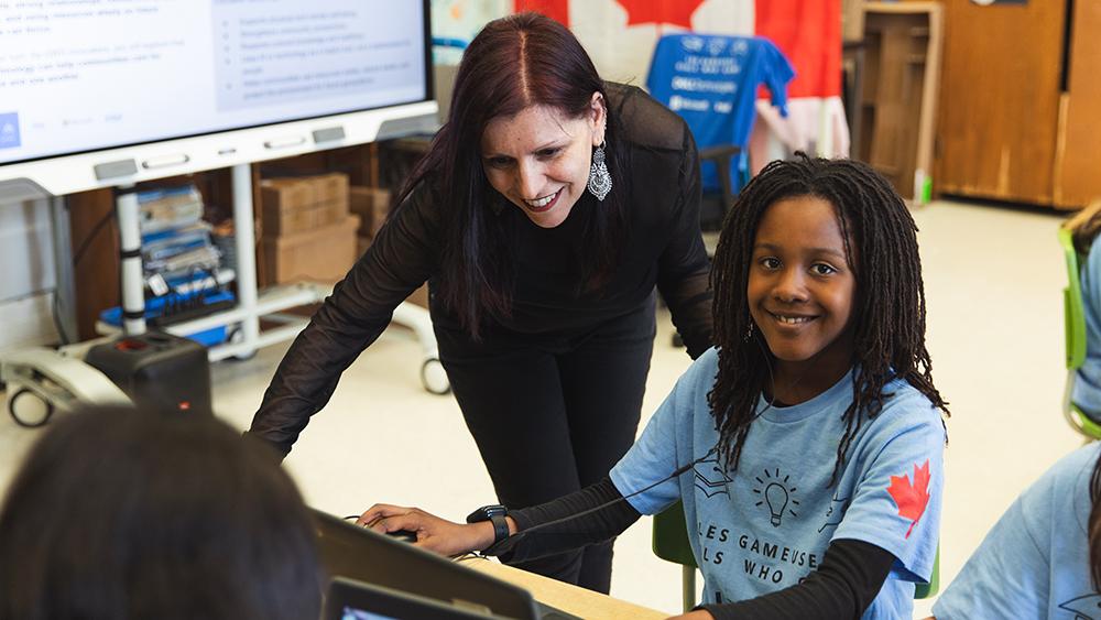 Teacher helping student using a laptop