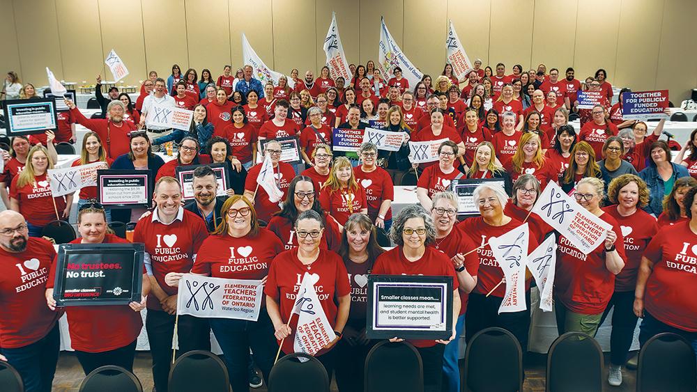 Gymnasium full of teachers wearing shirts and holding signs in support of solidarity