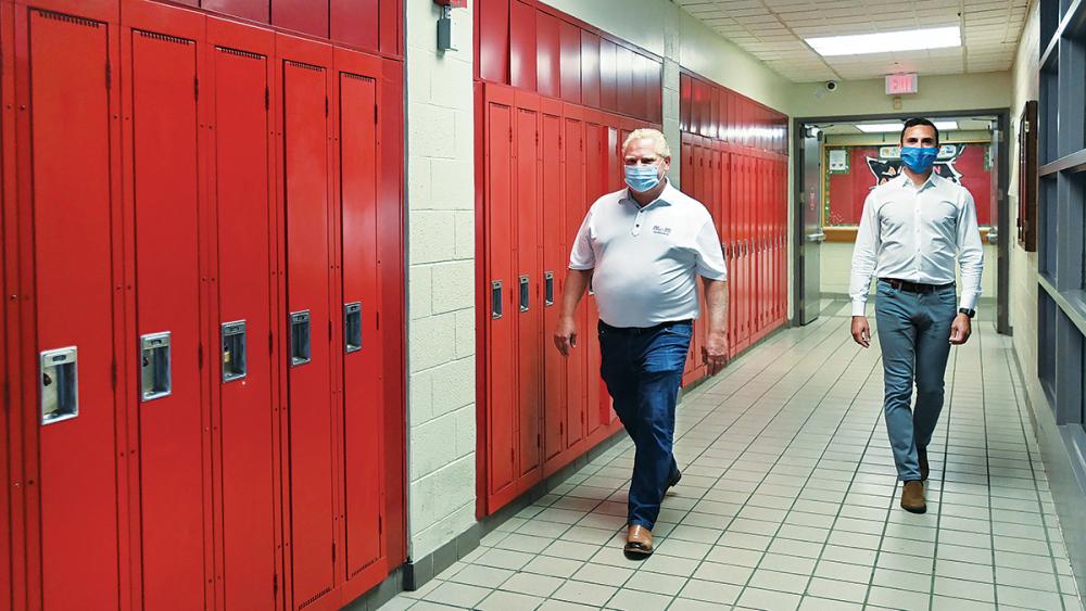 Doug Ford and Stephen Lecce walking down hallway with red lockers