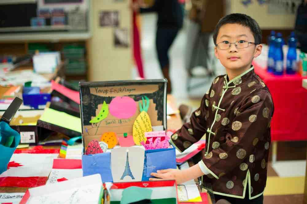 student standing next to diorama in classroom