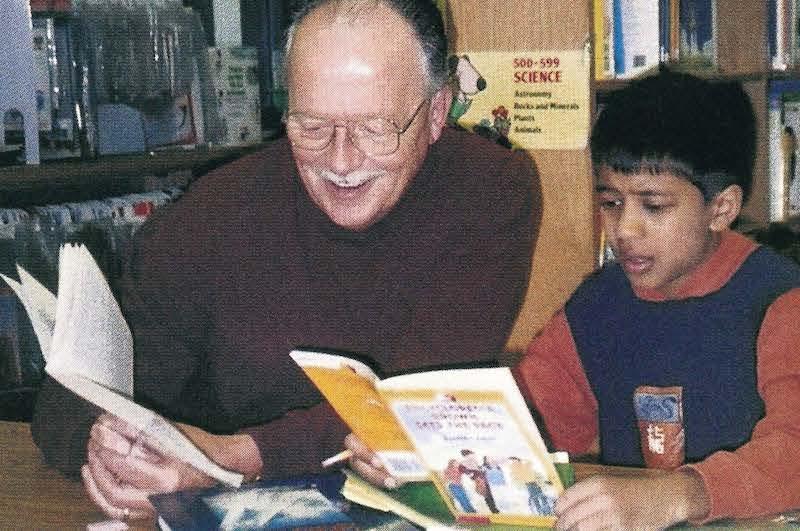 teacher reading with student in library