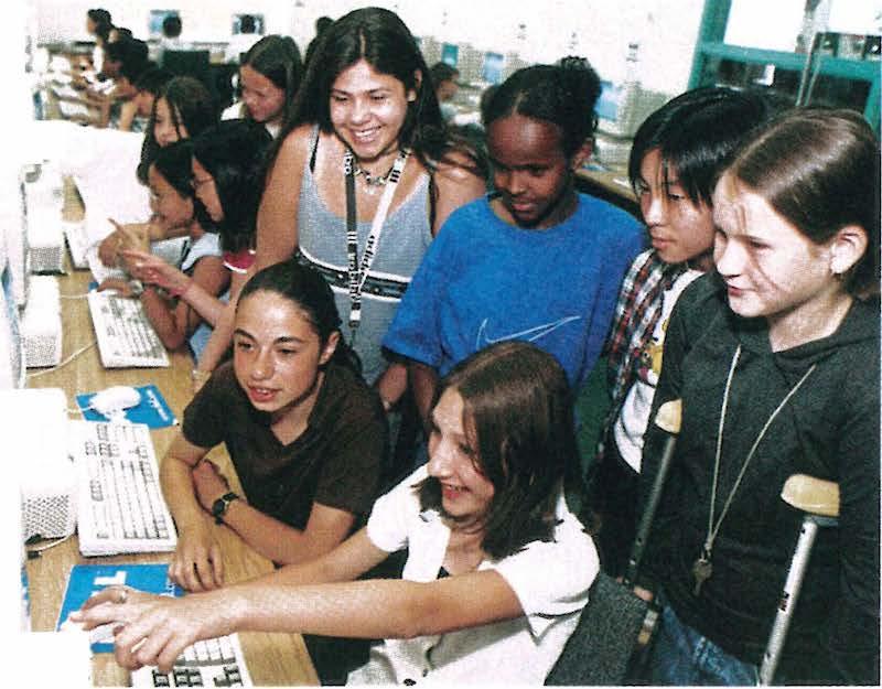 women and children in classroom using computer