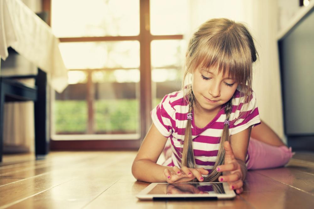 stock photo of young girl laying on floor using a tablet