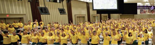 crowd of ETFO members wearing yellow shirts with hands in the air