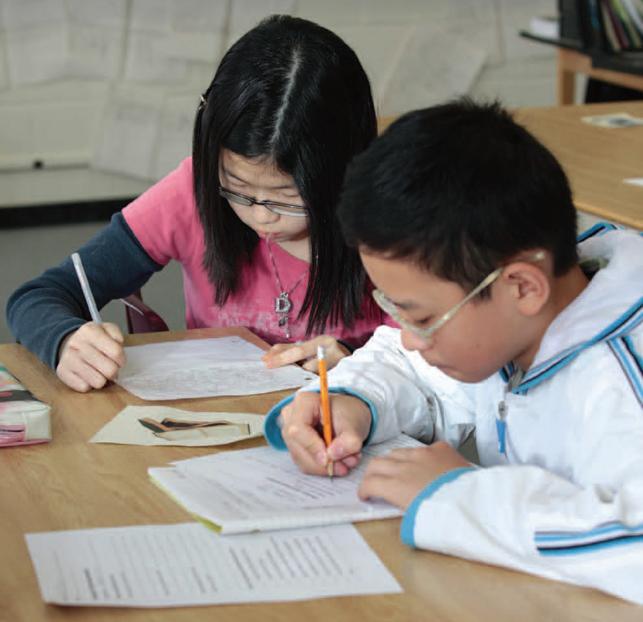 two students writing on paper with pencils in classroom