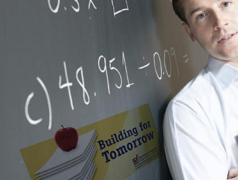 Teacher posing next to blackboard with mathematical equations written on it