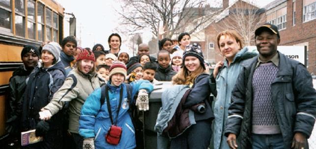 Teachers and students in winter clothing posing next to bus