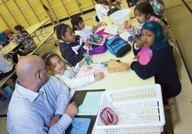 teacher sitting with students at large table in cafeteria