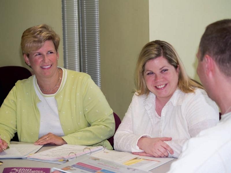 Teachers sitting together smiling at one another