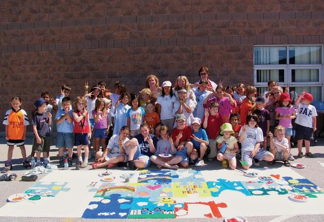 elementary class standing outside of school with artwork in front of them