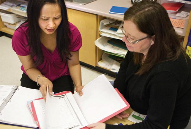 two teachers reading a report