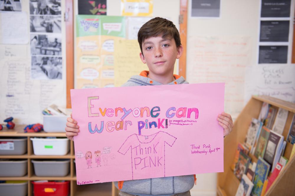 Male student holding paper that says "everyone can wear pink"