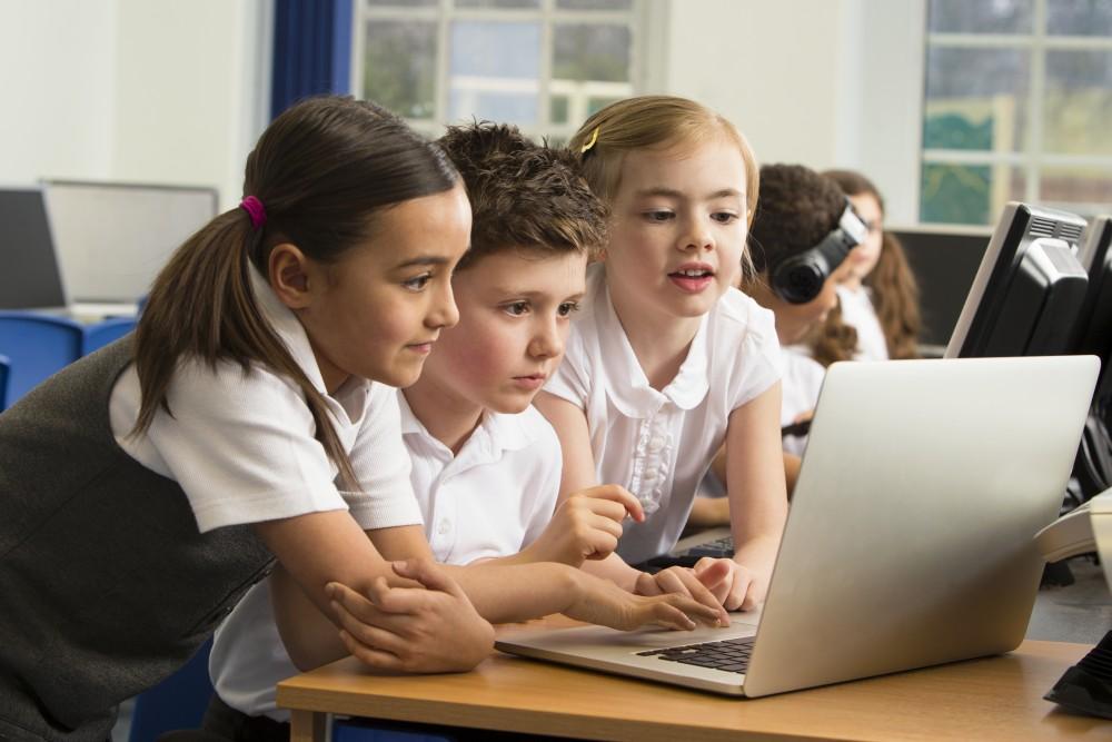 Young elementary students looking at laptop
