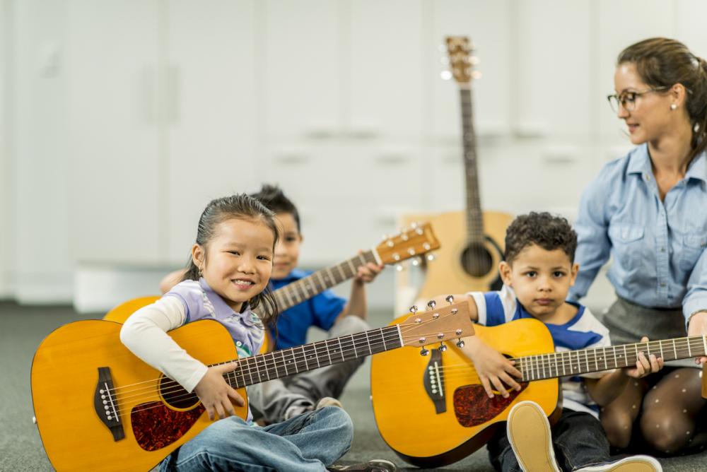 Elementary students learning music with acoustic guitars