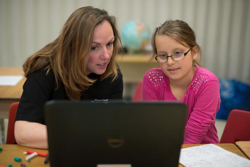 Teacher working with student using a laptop