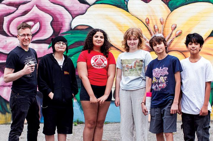 David Stocker and students posting in front of spray-painted mural