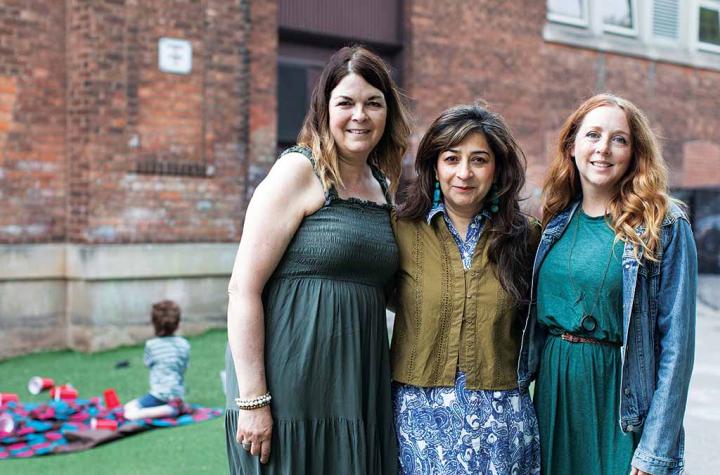 Three teachers posing outside of a school