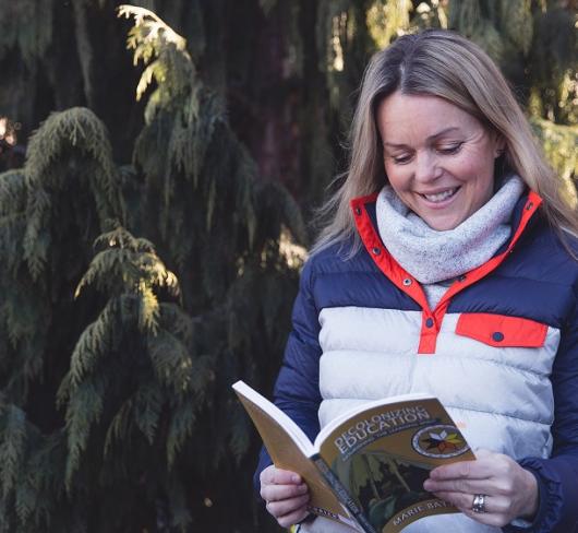Courtney Morgan standing in front of tree holding book