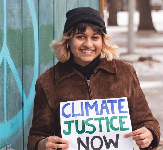 Savi Gellatly-Ladd holding "Climate Justice Now" sign