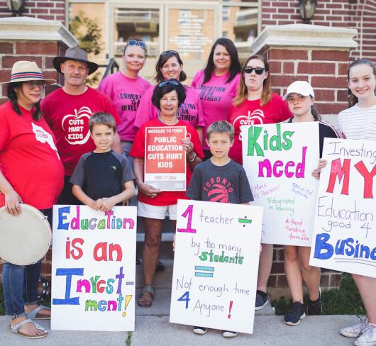 Teachers, parents, students and children holding rally signs