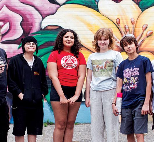 David Stocker and students posting in front of spray-painted mural