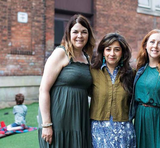 Three teachers posing outside of a school