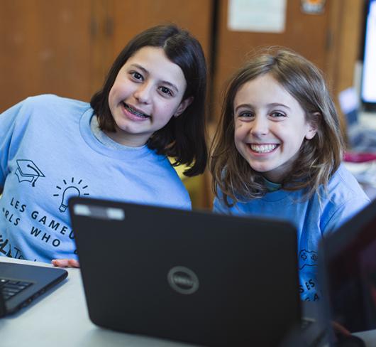 Two girls in classroom using a laptop