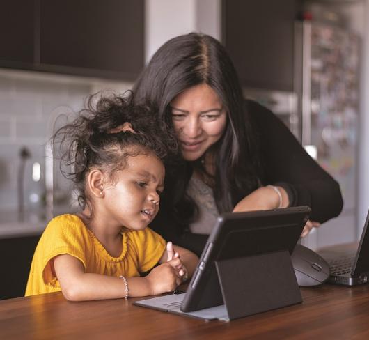Parent showing child how to use laptop